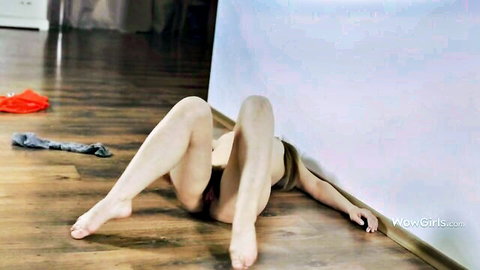 Slim woman lying on floor with legs spread wide exposing shaved pussy in solo pose