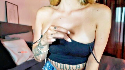 Blonde tattooed Kira Gold teasing cleavage in black crop top