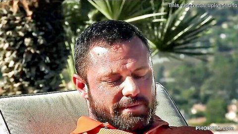Sweaty bearded man in orange shirt outdoors, teasing gay encounter