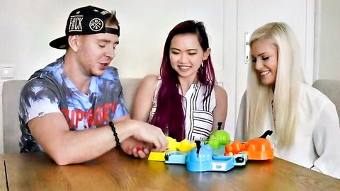 Two smiling pornstars with a guy playing Hungry Hippos game