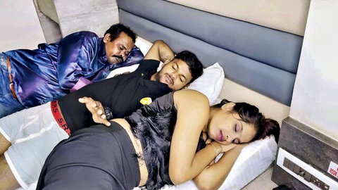 Sexy Indian woman in tight black shorts sleeping between older husband and young lover on hotel bed