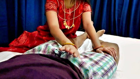 Indian woman in red saree gives sensual handjob to big cock bulging through plaid dhoti on bed