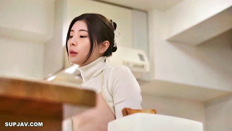 Busty Japanese MILF in tight white turtleneck smiling seductively at kitchen table