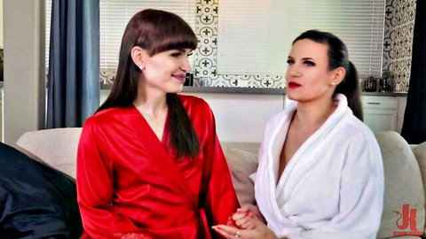 Two elegant women in silk robes holding hands intimately