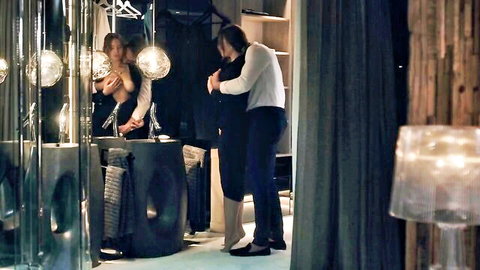 Intimate couple embrace in mirror, woman in sleek black dress teasing reveal