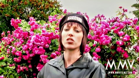 Mature brunette in black leather jacket and beret speaking amid pink roses