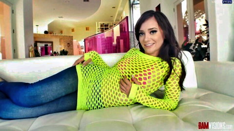 Skinny young brunette teases in sheer neon green fishnet dress exposing small tits on couch