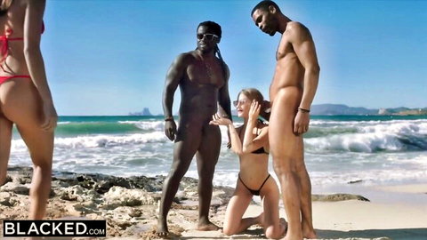 Two white women in bikinis kneel before nude black bulls on sunny beach