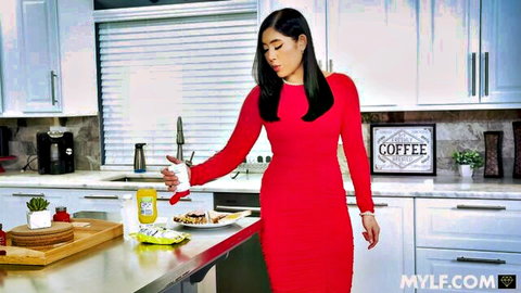 Sexy Asian MILF in tight red dress squirting yellow mustard on food in kitchen
