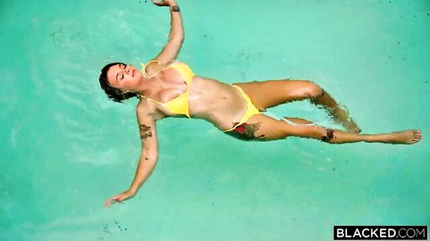 Curvy tattooed brunette in skimpy yellow bikini floating in pool teasing huge tits cleavage