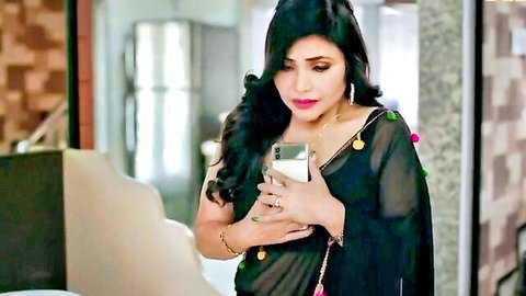 Curvy brunette in sheer black saree holding phone selfie exposing deep cleavage