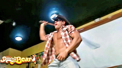 Muscular cowboy dancer in open plaid shirt posing with mallet at Dancing Bear party