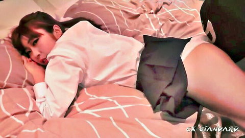 Cute Asian teen in schoolgirl skirt lying on bed flashing white panties seductively