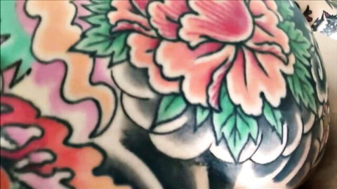 Close-up of vibrant pink peony tattoo on smooth pale skin