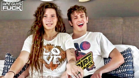 Young smiling brunette teen with long dreads and curly haired guy on bed in tight shirts
