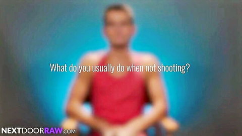 Muscular gay hunk in red tank top sits for interview on NextDoorRaw asking what he does off camera