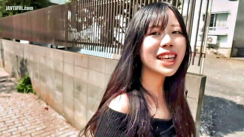 Smiling young Asian woman with long black hair in off-shoulder top outdoors