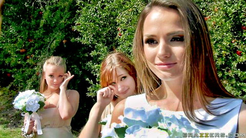 Sexy brunette bride with blonde and redhead bridesmaids posing playfully outdoors in wedding dresses