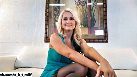 Blonde MILF in tight turquoise dress sitting seductively on casting couch