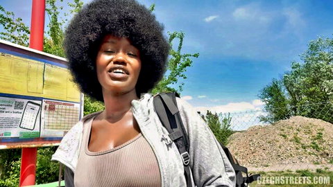 Curvy black babe with huge afro and big tits smiling teasing cleavage at street bus stop
