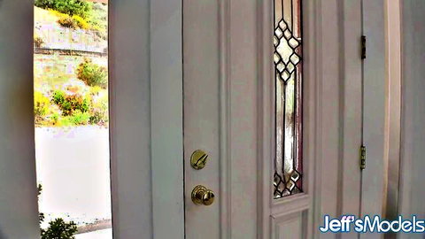 Open white front door with stained glass revealing lush green garden outside