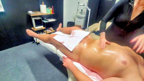 Female masseuse oils and massages naked muscular man's torso in erotic session