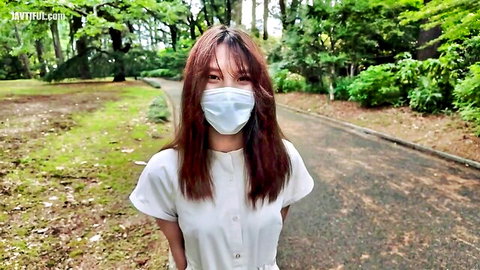 Young Japanese woman in white blouse and mask in sunny park POV