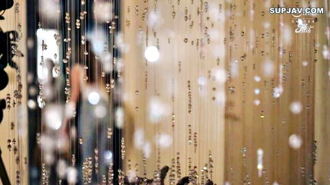 Uncensored Asian babe teasing with big boobs and ass behind beaded curtain