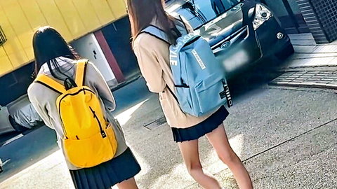 Two Japanese schoolgirls in pleated skirts and backpacks walking from behind