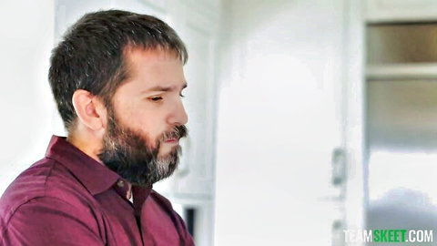 Bearded man in maroon shirt in kitchen, teaser for Avery Black squirting stepdaughter video