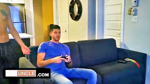 Shirtless tanned hunk reaches for gamer dude's crotch bulge while he plays on couch
