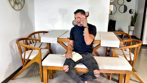 Fit middle-aged man in black tee and ripped jeans on phone call with book