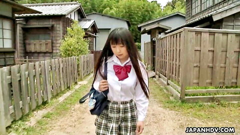 Japanese schoolgirl in uniform walking through rural village path