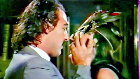 Man in suit passionately kissing brunette woman wearing exotic feathered mask close-up
