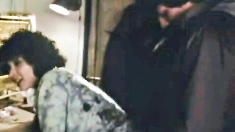Retro 1983 Sulka's Wedding scene: curly-haired woman bent over desk with man behind