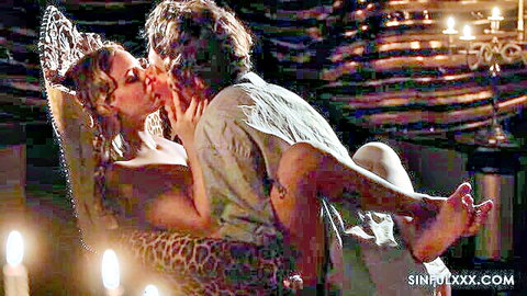 Blonde woman passionately kissing curly-haired man in intense topless embrace