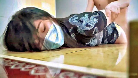 Masked Asian woman in dragon shirt lies prone on apartment floor with bare ass up as naked man fingers her pussy doggy style.