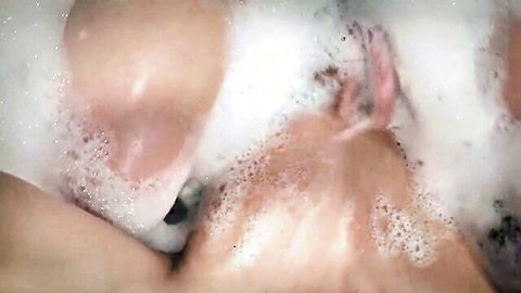 Steamy amateur couple in foamy bathtub with bubbles obscuring nude bodies and tits