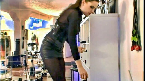 Brunette femdom in sheer black top, corset, mini skirt bending over