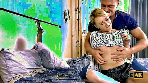 Mature blonde woman embraced by man, topless in striped shirt and socks