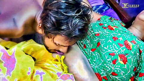 South Asian man passionately kissing woman's neck in steamy green floral saree embrace