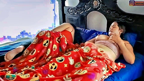 Busty brunette topless on bed spreading legs under red emoji blanket exposing natural big tits