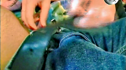 Woman's red-nailed hand grips thick erect cock pulled from blue jeans closeup