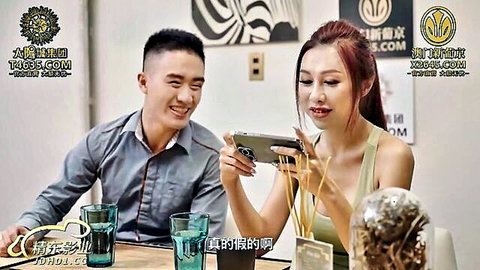Smiling Asian babe with cleavage eating noodles at table with boyfriend