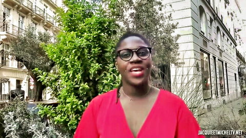 Smiling ebony babe with big tits in low-cut red top outdoors