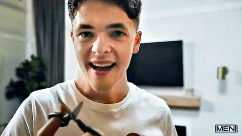 Troye Dean smiling playfully holding scissors in white t-shirt