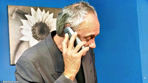 Mature old man in gray suit talking on flip phone closeup