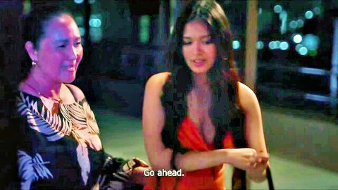 Asian MILF and young woman in red dress talking intimately at night