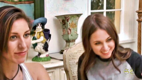 Two smiling brunettes in casual tops for hot lesbian tease