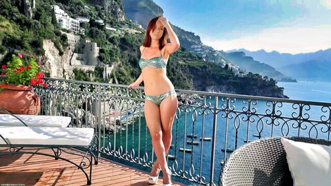 Petite redhead with small tits poses seductively in skimpy bikini on sunny outdoor balcony overlooking sea